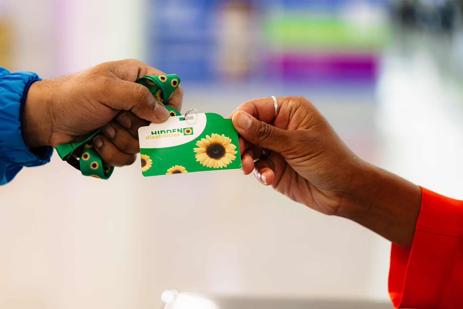 A hand is exchanging a Sunflowers HIDDEN DISABILITIES badge.