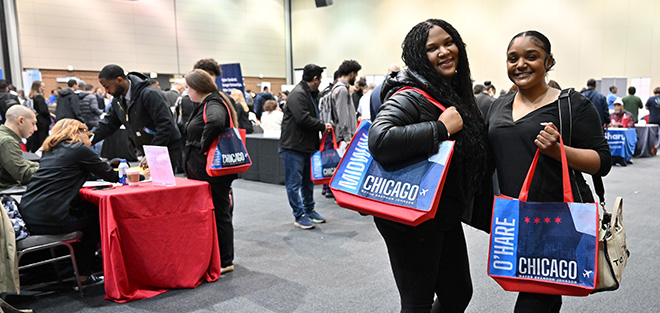 Photograph of two woman standing holding tote bags at the Airport Expo event